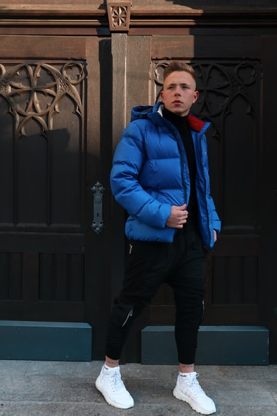 身穿蓝色夹克的男子站在黑色木门附近